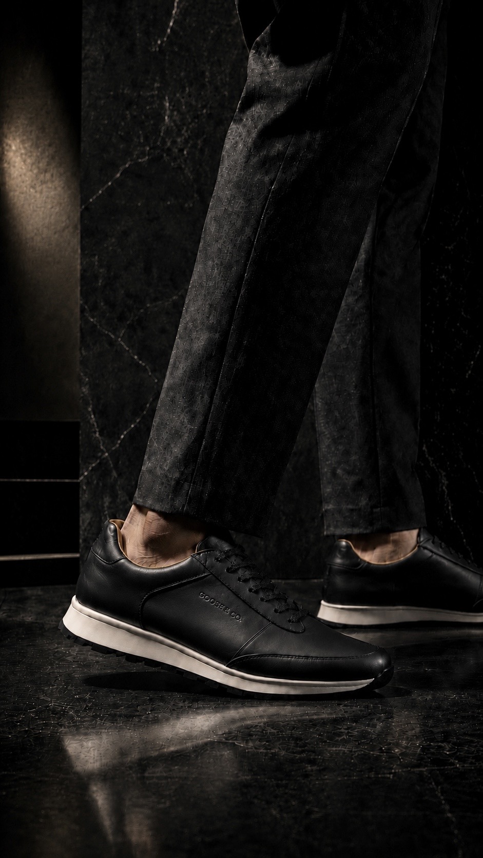 A single sneaker on a polished floor under raking warm light, casting a long shadow.
